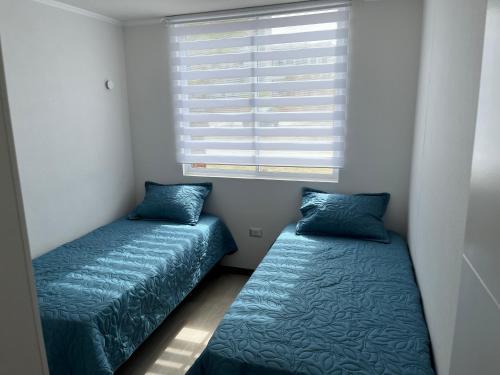 2 camas en una habitación pequeña con ventana en Departamento en La Serena en La Serena