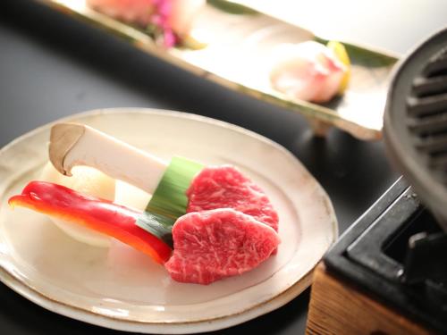 a piece of meat on a plate on a table at Ryokan Sakaya in Nozawa Onsen