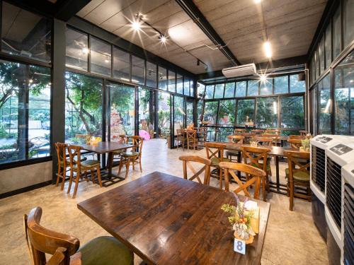 a restaurant with wooden tables and chairs and windows at Crystal Resort Korat in Nakhon Ratchasima