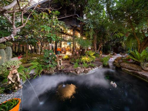 a garden with a pond in front of a building at Crystal Resort Korat in Nakhon Ratchasima