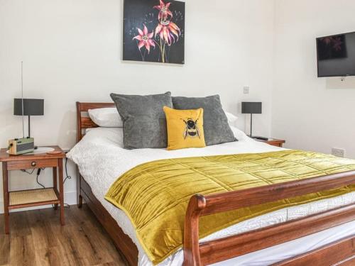 ein Schlafzimmer mit einem Bett mit einer gelben Decke und 2 Lampen in der Unterkunft Blundens Dawmill in Chichester
