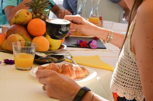 une femme assise à une table avec une assiette de nourriture dans l'établissement Relais Villa Olivi, à Costermano