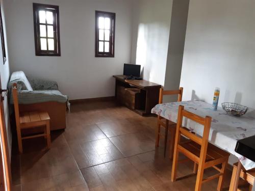ein Wohnzimmer mit einem Tisch und einem Schreibtisch mit einem Laptop in der Unterkunft Casa Cantinho da Roça Recanto Lobo Guará in Gonçalves