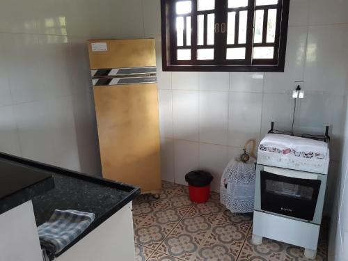 uma pequena cozinha com um fogão e uma janela em Casa Cantinho da Roça Recanto Lobo Guará em Gonçalves