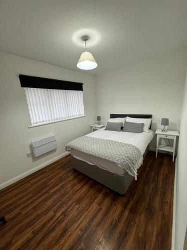 een slaapkamer met een bed, houten vloeren en een raam bij Manchester Cosy flat close to City Centre and City stadium in Manchester