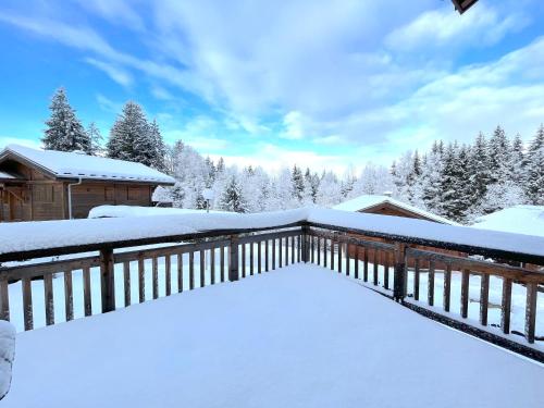a deck covered in snow with trees in the background at Chalet L'AS DE CARROZ in Arâches-la-Frasse