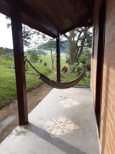 a porch with a hammock and a view of a field at Casa Cantinho da Roça Recanto Lobo Guará in Gonçalves