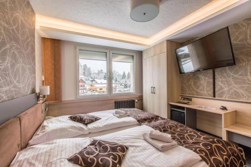a bedroom with two beds and a flat screen tv at Pension Böhmerwald in Železná Ruda