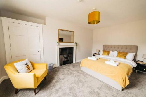 a bedroom with a large bed and a yellow chair at Central 4-bed House, 10 min Walk to Sights in Bath