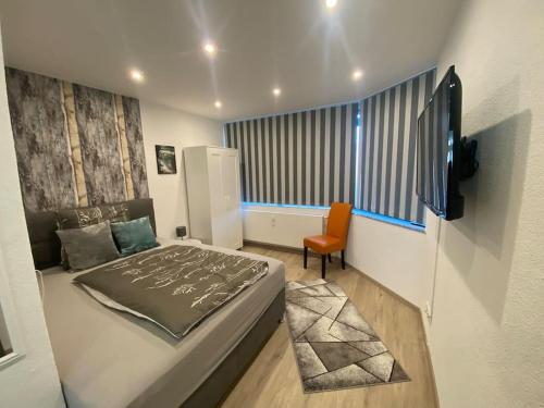 a bedroom with a bed and a tv and a chair at Ferienwohnung Sonnenblume in Memmingen