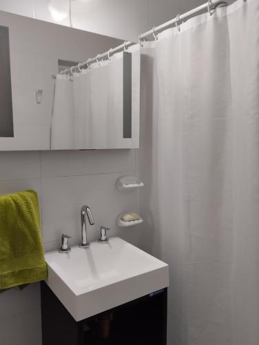 La salle de bains blanche est pourvue d'un lavabo et d'une douche. dans l'établissement Departamento Céntrico, à Esquel