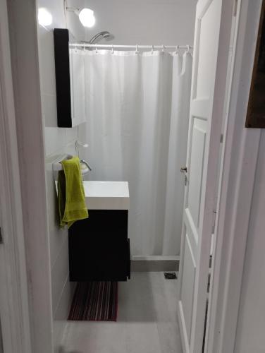 La salle de bains blanche est pourvue d'un lavabo et d'une douche. dans l'établissement Departamento Céntrico, à Esquel