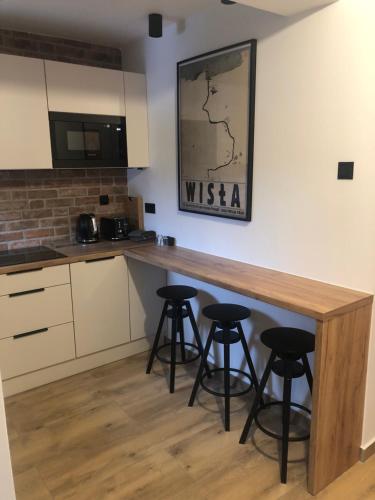 a kitchen with a wooden counter and stools at Wiślańskie Doliny in Wisła