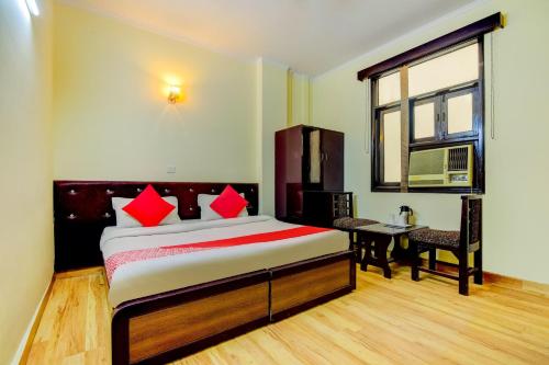 a bedroom with a bed and a desk and a window at OYO Hotel Delhi Darbar in New Delhi