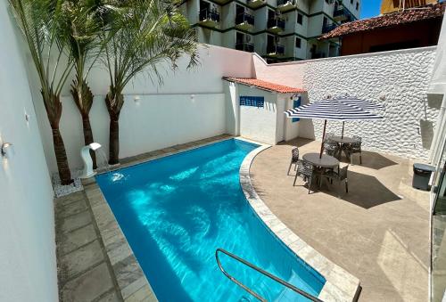 a swimming pool with a table and a umbrella at Kyros Pousada in Maceió