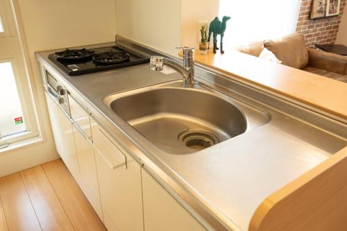 un lavandino in acciaio inossidabile in una cucina con piano cottura di Relax Lounge TOKYO a Tokyo