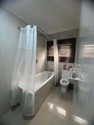 uma casa de banho com uma banheira, um WC e uma cortina de chuveiro. em Lemajy Apartments em Solwezi