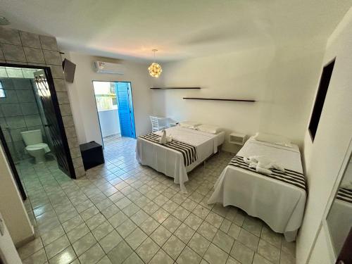 a hotel room with two beds and a bathroom at Kyros Pousada in Maceió