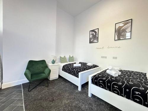 a bedroom with two beds and a green chair at Chic Downtown Flat in Dudley Near Attractions in Birmingham