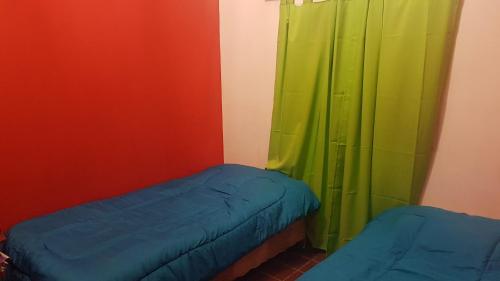 a room with two beds and a green curtain at Casa Hogar in Monterrico