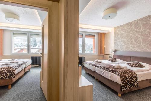 2 Betten in einem Zimmer mit 2 Fenstern in der Unterkunft Pension Böhmerwald in Železná Ruda