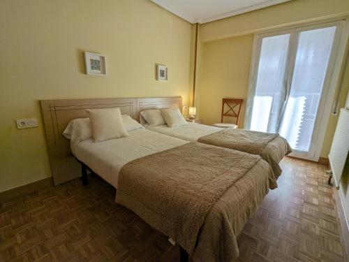 a bedroom with two beds and a large window at Zumaia Basque Alai in Zumaia