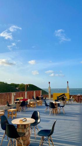 a deck with tables and chairs and the ocean at Pousada Delta Village in Tutóia