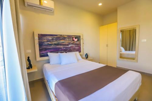1 dormitorio con 1 cama blanca y una pintura en la pared en Inkanto Luxury Hotel en Mahahual