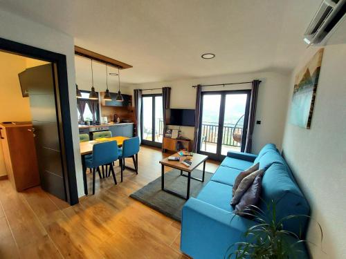 a living room with a blue couch and a kitchen at Apartmani Višegradski pogled in Višegrad