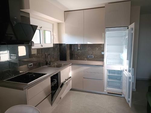 Digital Nomads Apartments في بار: مطبخ مع دواليب بيضاء وثلاجة مفتوحة