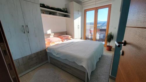 a bedroom with a bed and a large window at Goldview Apartmani in Zlatibor