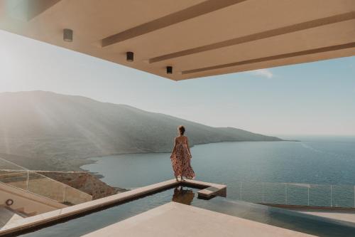 Kobieta stojąca na dachu budynku patrząca na wodę w obiekcie Happy Cretan Suites w mieście Agia Pelagia