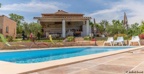 a swimming pool with chairs and a house at Gites Les Granges De Flolie in Beauteville