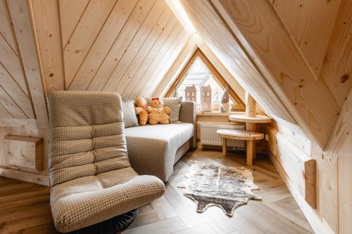 a room with a couch and a chair in a attic at Brzozowa Osada - Premium Chalets Zakopane in Zakopane