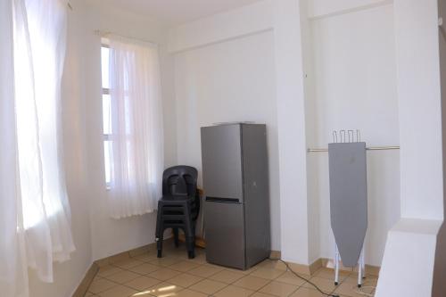 eine Küche mit einem Kühlschrank und einem Stuhl in einem Zimmer in der Unterkunft Grandborough in Durban