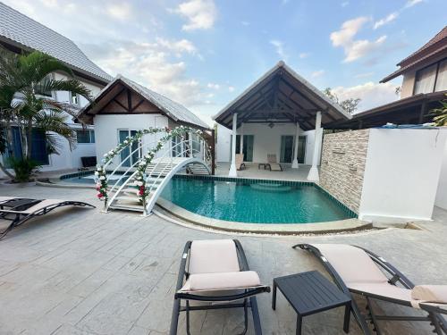 a swimming pool with chairs and a staircase next to a house at Pheonix Golf Pool Resort Villa in Ban Huai Yai