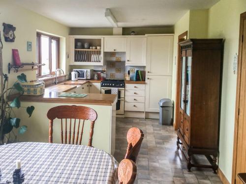 a kitchen with white cabinets and a table with chairs at Scridain View in Bunessan