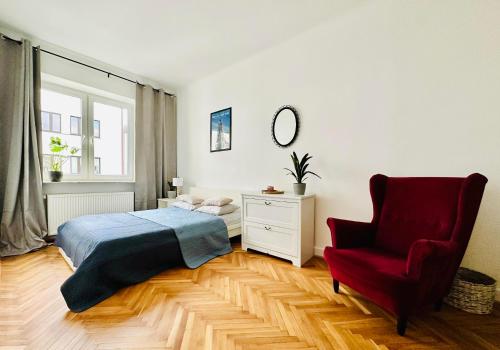 1 dormitorio con 1 cama y 1 silla roja en Baja Apartment Warsaw en Varsovia