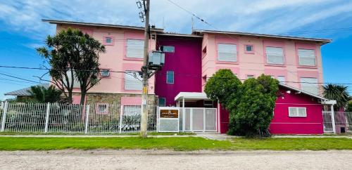 une maison rose avec une clôture devant elle dans l'établissement Gran Hotel de los Acantilados, à Mar del Plata