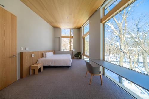 una camera da letto con un letto, una scrivania e una finestra di Villa Lily by Hakuba White Fox Company a Hakuba