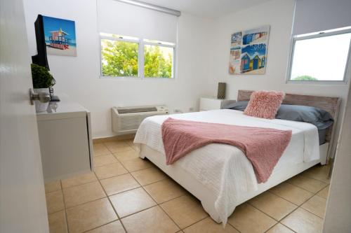 a white bedroom with a bed and two windows at Luxury Apartment with Ocean Views in Fajardo
