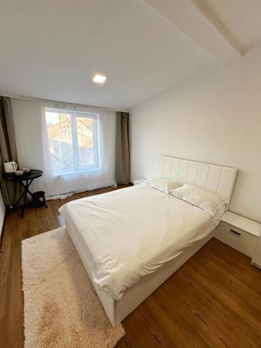 a bedroom with a large white bed with a window at Stone Residence in Braşov