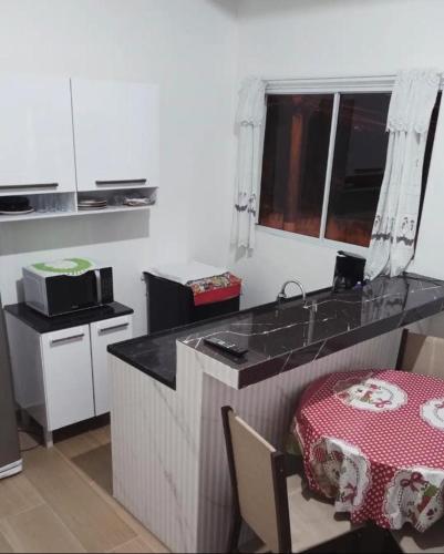 a kitchen with a counter with a table and a sink at Chalé Ilhabela in Ilhabela