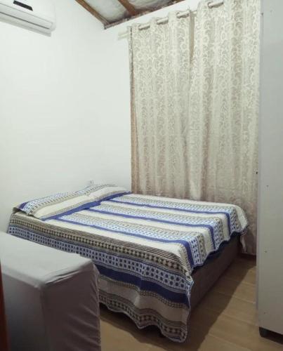 Cama pequeña en habitación con cortina en Chalé Ilhabela, en Ilhabela