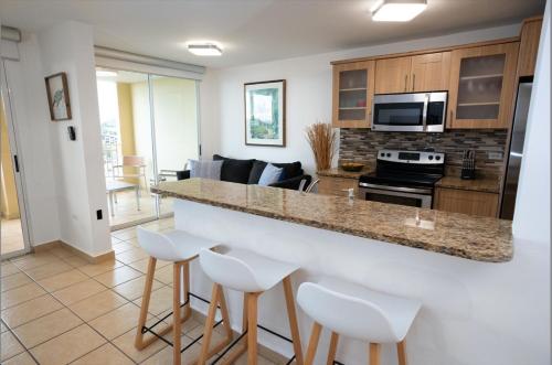 a kitchen and living room with a counter and stools at Luxury Apartment with Ocean Views in Fajardo