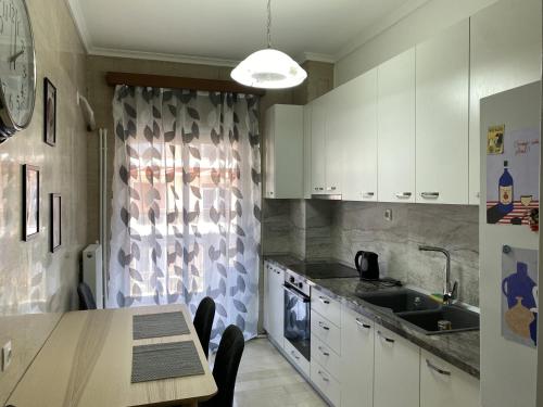 - une cuisine avec des placards blancs, une table et un évier dans l'établissement Serene Apartment with Breathtaking Sea View, à Thessalonique