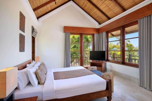 a bedroom with a bed and a television in a room at Karma Kandara in Uluwatu