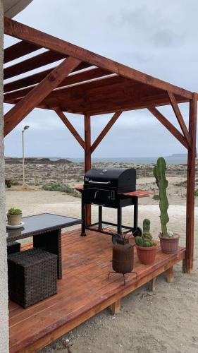 a picnic shelter with a grill on a wooden deck at Entre Dunas y Caracolas in Punta de Choros