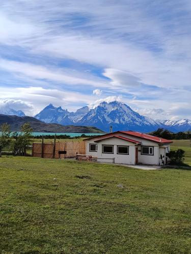 ein Haus auf einem Feld mit Bergen im Hintergrund in der Unterkunft CABAÑA ESTANCIA LAZO in Torres del Paine