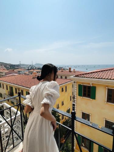 a woman in a white dress looking out over a city at Mellon OASIS Phu Quoc in Phu Quoc